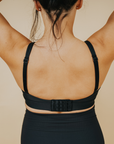 Back view of active mum wearing black nursing sports bra with crossover straps