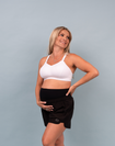 Happy mum holding her baby bump wearing a supportive breastfeeding bra and postpartum shorts